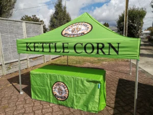 A green branded gazebo with a table cloth for Kettle Corn