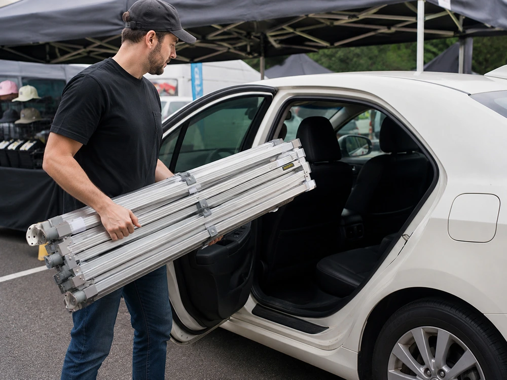 Market vendor lifting a packed aluminium gazebo frame bag out of a car boot