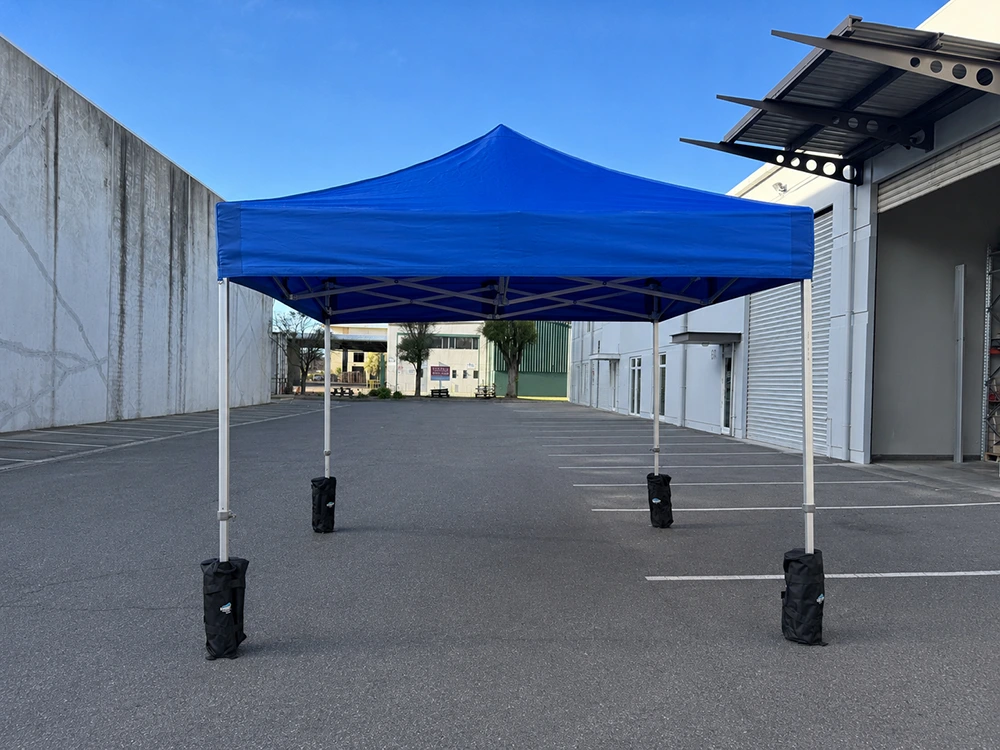 Hercules gazebo weight bag anchored to frame leg on a hard surface at an outdoor event