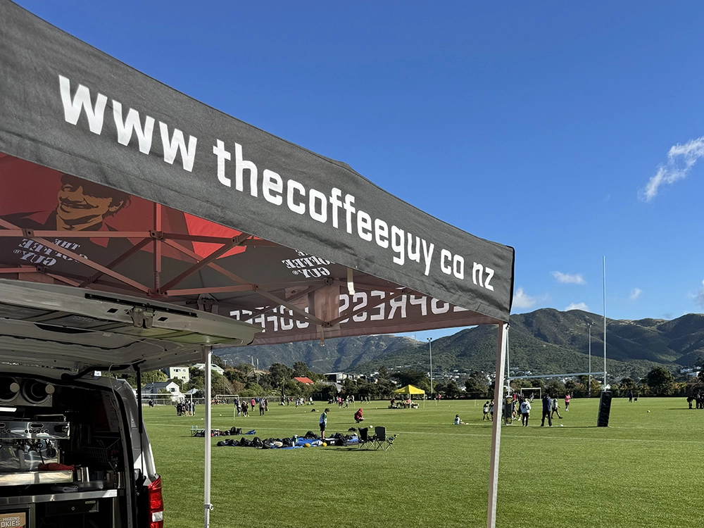 Coffee Guy Petone Hercules gazebo ratchet-strapped to van standing firm in strong Wellington wind at an outdoor event